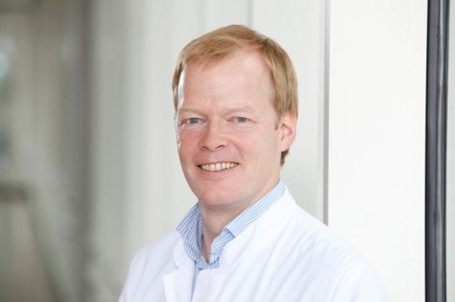 Porträt von Prof. Nicolas Feltgen, der einen weißen Kittel trägt